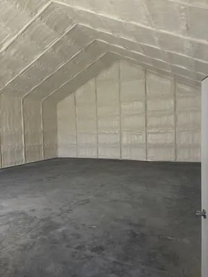 Empty room with gray concrete floor and walls and ceiling covered in light gray insulation.