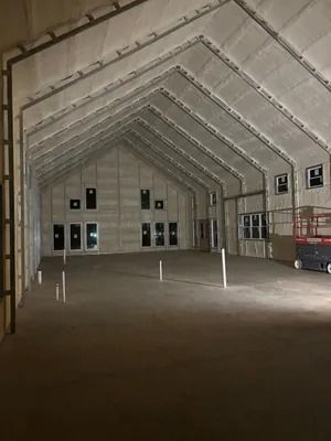 Empty, unfinished building interior with angled ceiling and multiple doorways. Gray walls and floor.