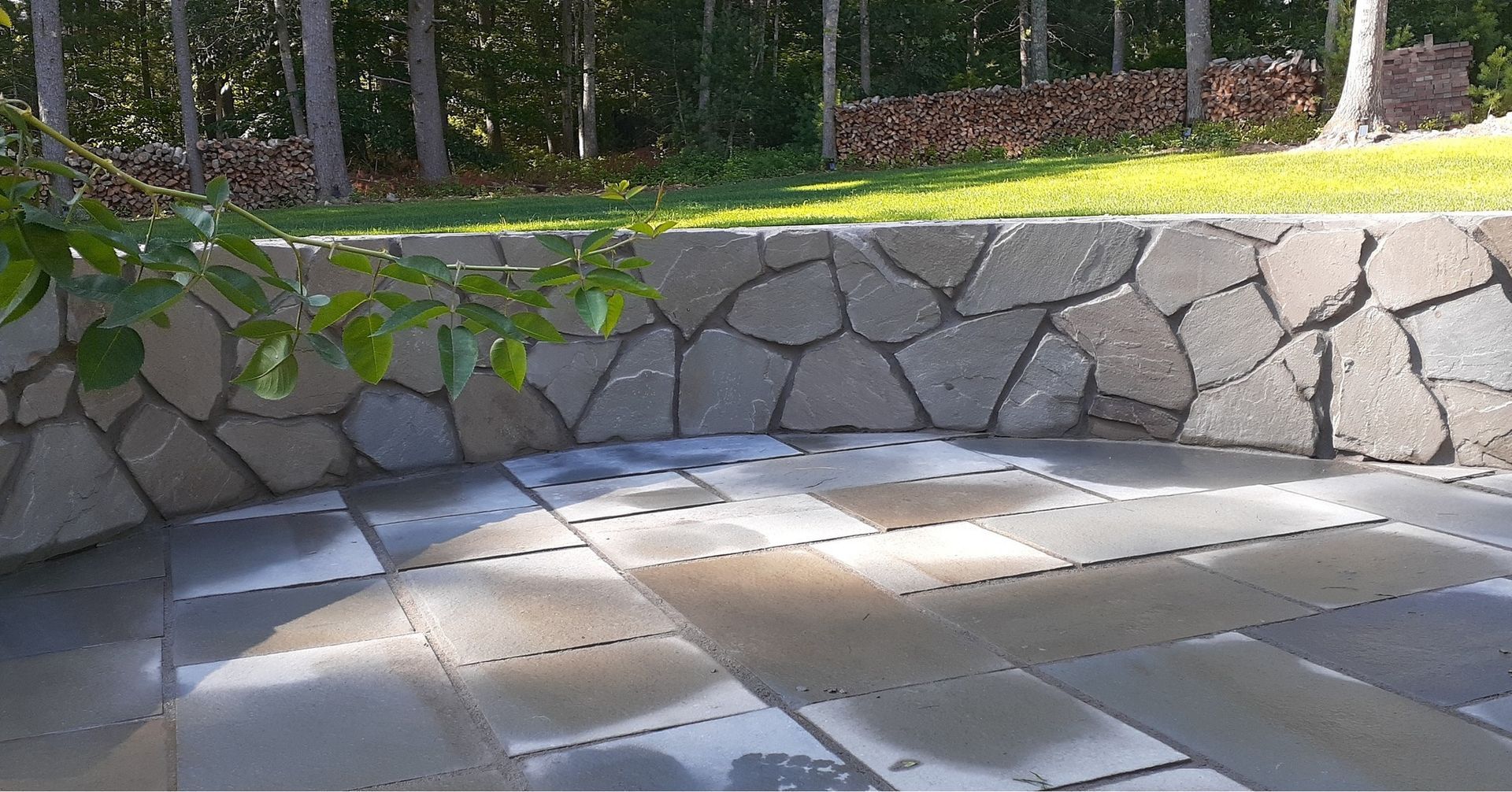 A stone wall surrounds a patio with a stone wall in the background.