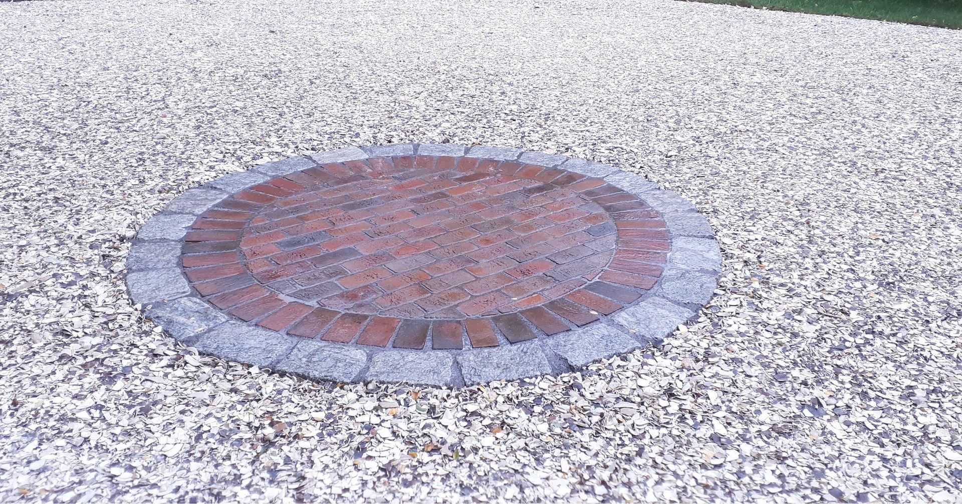 A circle of bricks on a gravel driveway