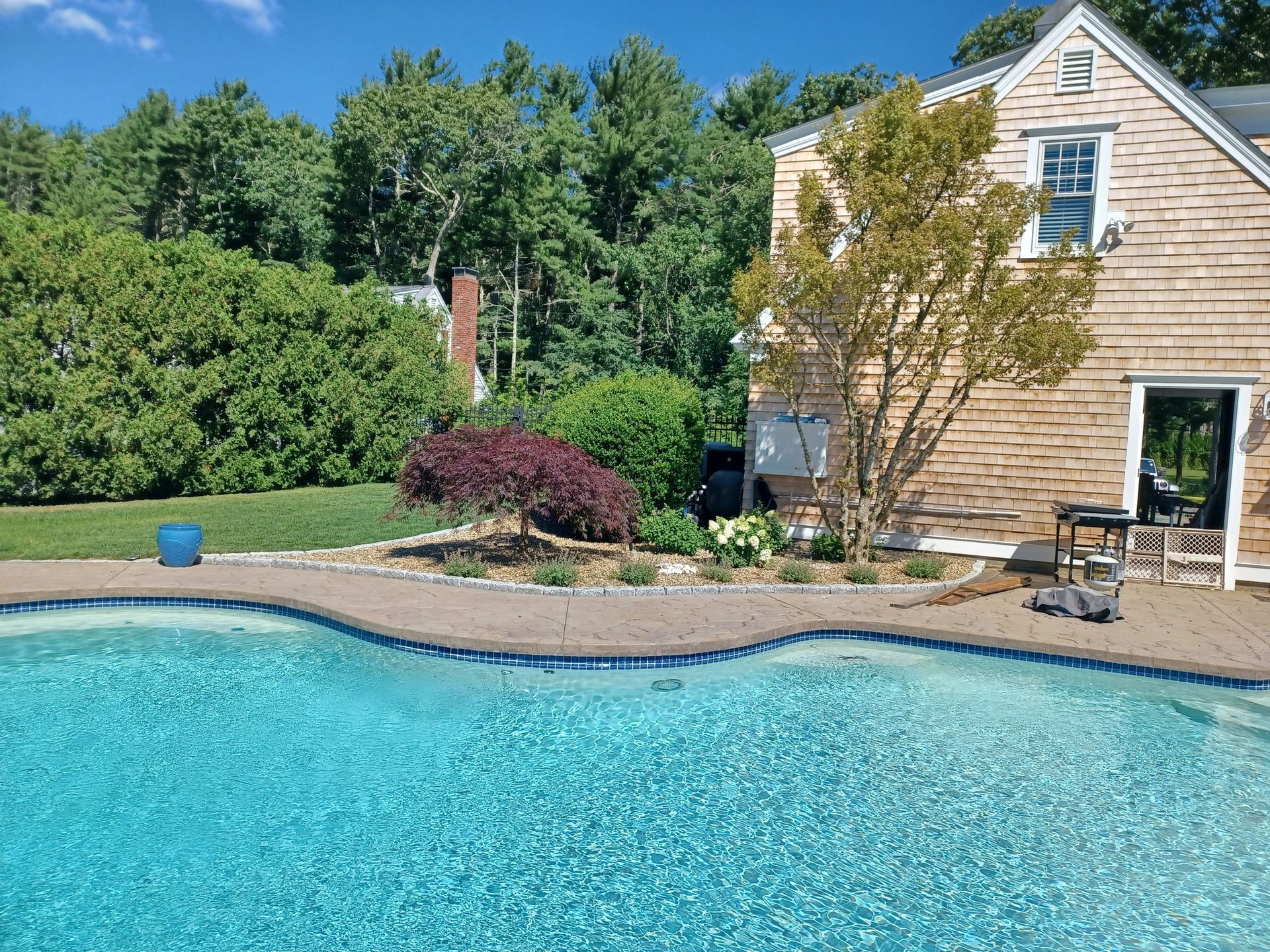 There is a large swimming pool in the backyard of a house.