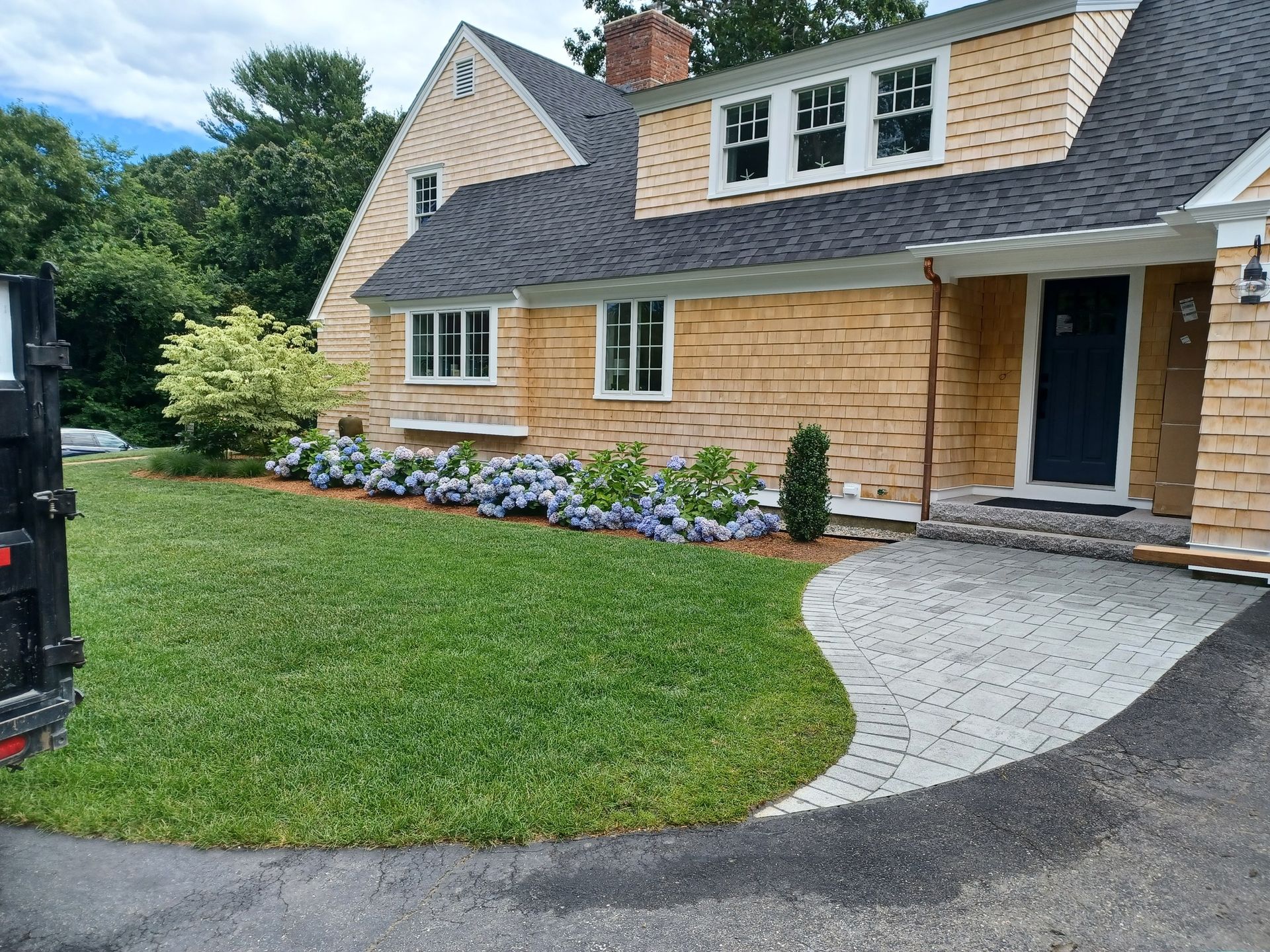 A large house with a black roof is sitting on top of a lush green lawn.