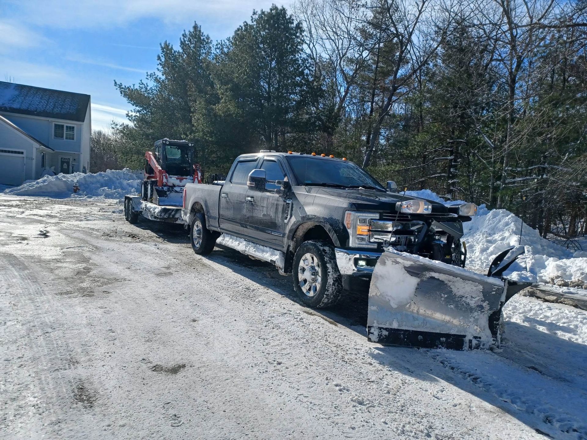 A truck with a snow plow attached to it is parked on the side of the road.