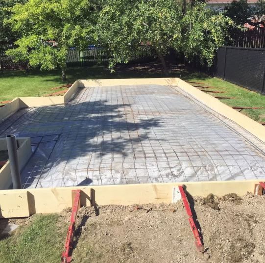 A concrete driveway is being built in a backyard.