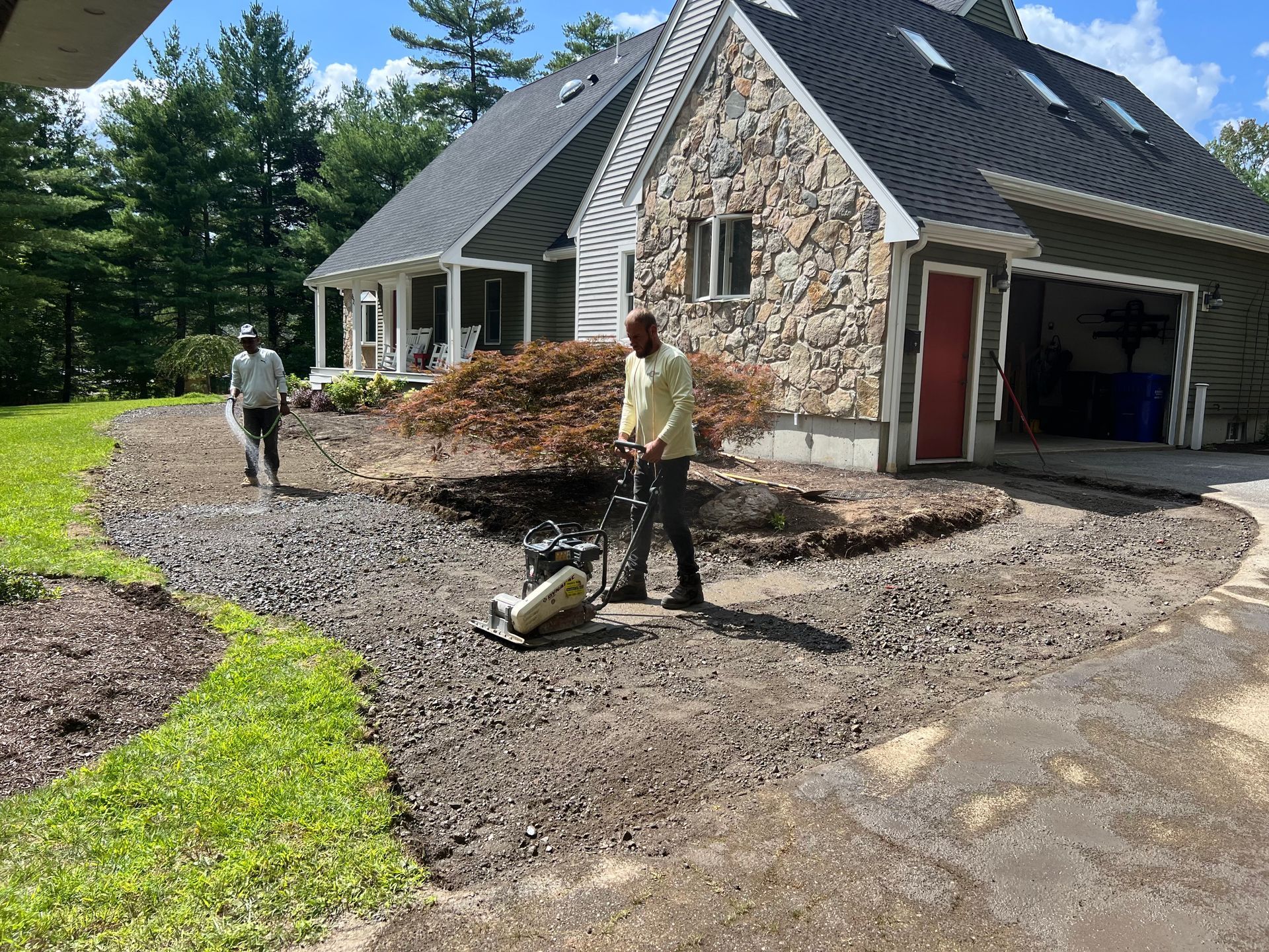 A man is working on a driveway in front of a house.