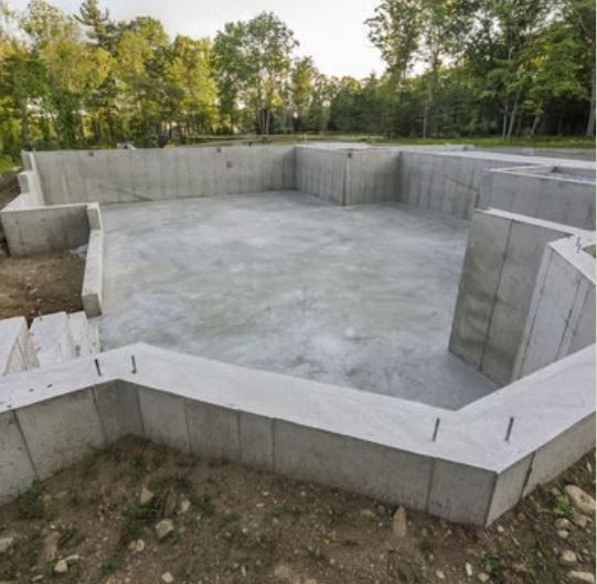 A large concrete foundation is being built in the middle of a forest.