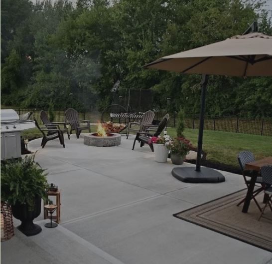 A patio with a fire pit and chairs and an umbrella