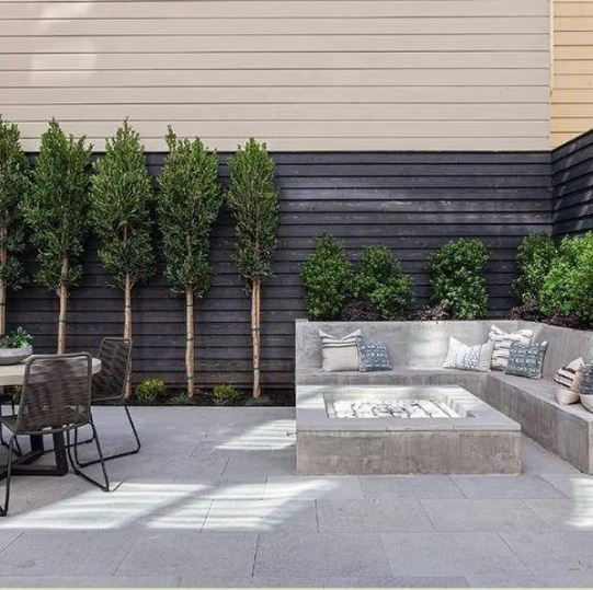 A patio with a couch, table, chairs and a fire pit.