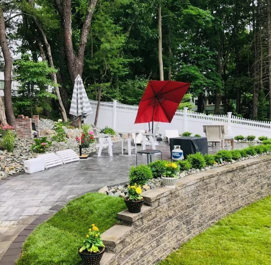A patio with a red umbrella and potted plants