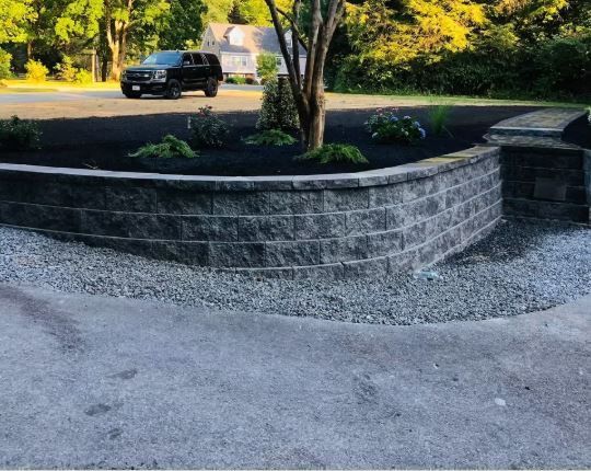 A black truck is parked in a driveway next to a brick wall.
