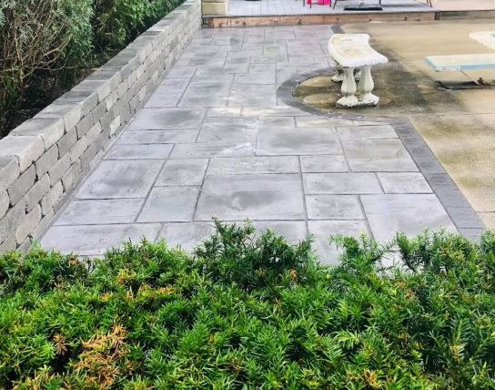 A patio with a bench and a brick wall in the background.