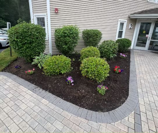 A garden with flowers and bushes in front of a building.