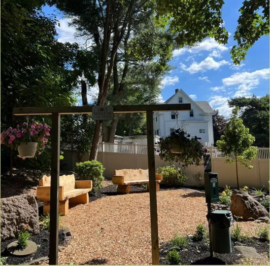 A wooden swing in a yard with a house in the background
