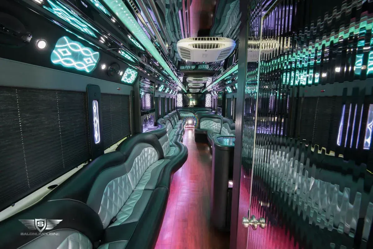 Interior of a limousine with black and gray seating, neon lights, and mirrored ceiling.