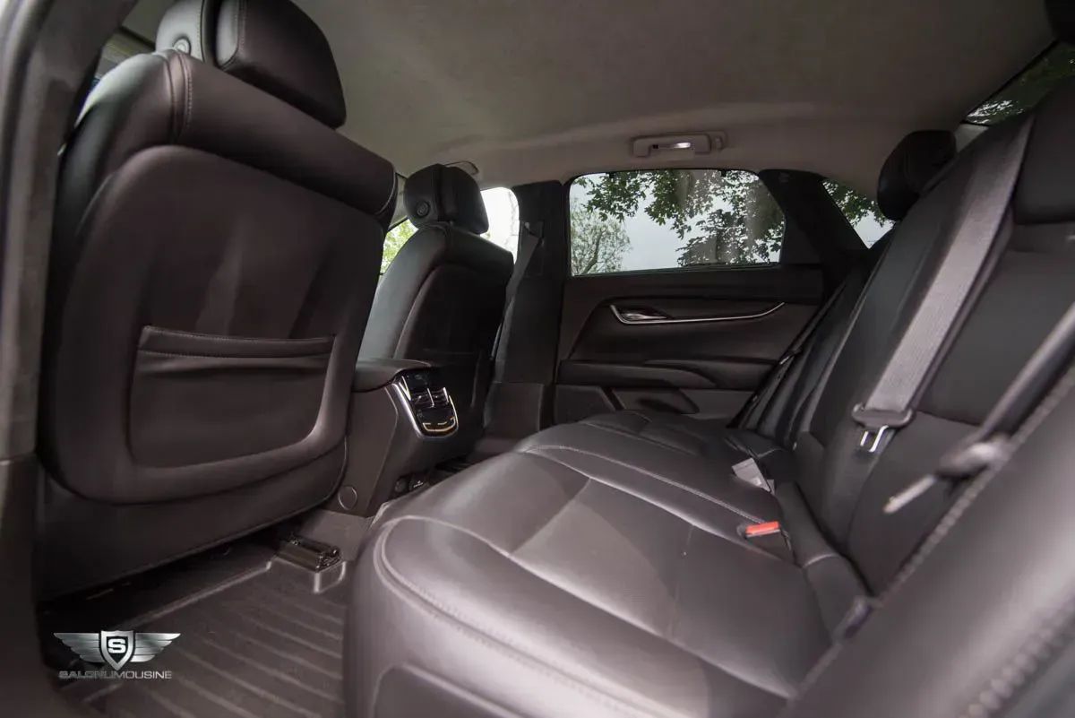 Backseat of a black car, showing leather seats and interior details.