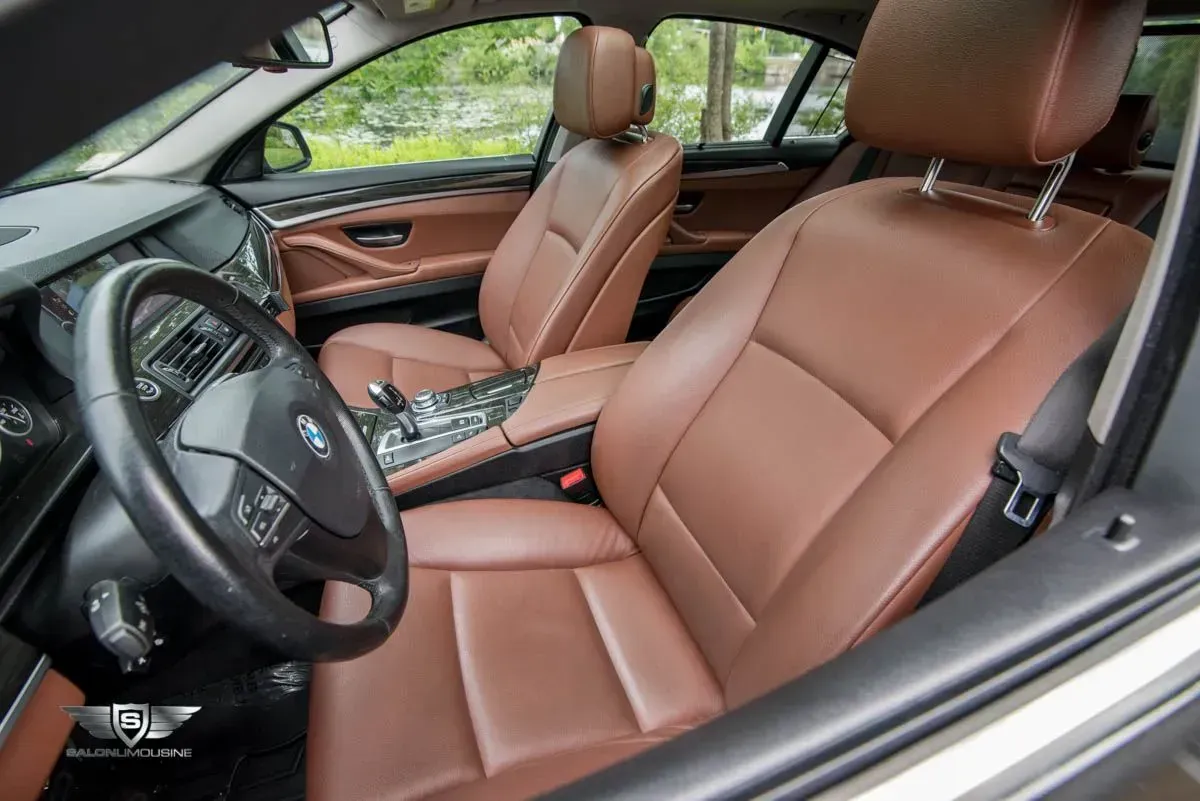 Brown leather interior of a BMW sedan, including seats, dashboard, and steering wheel.