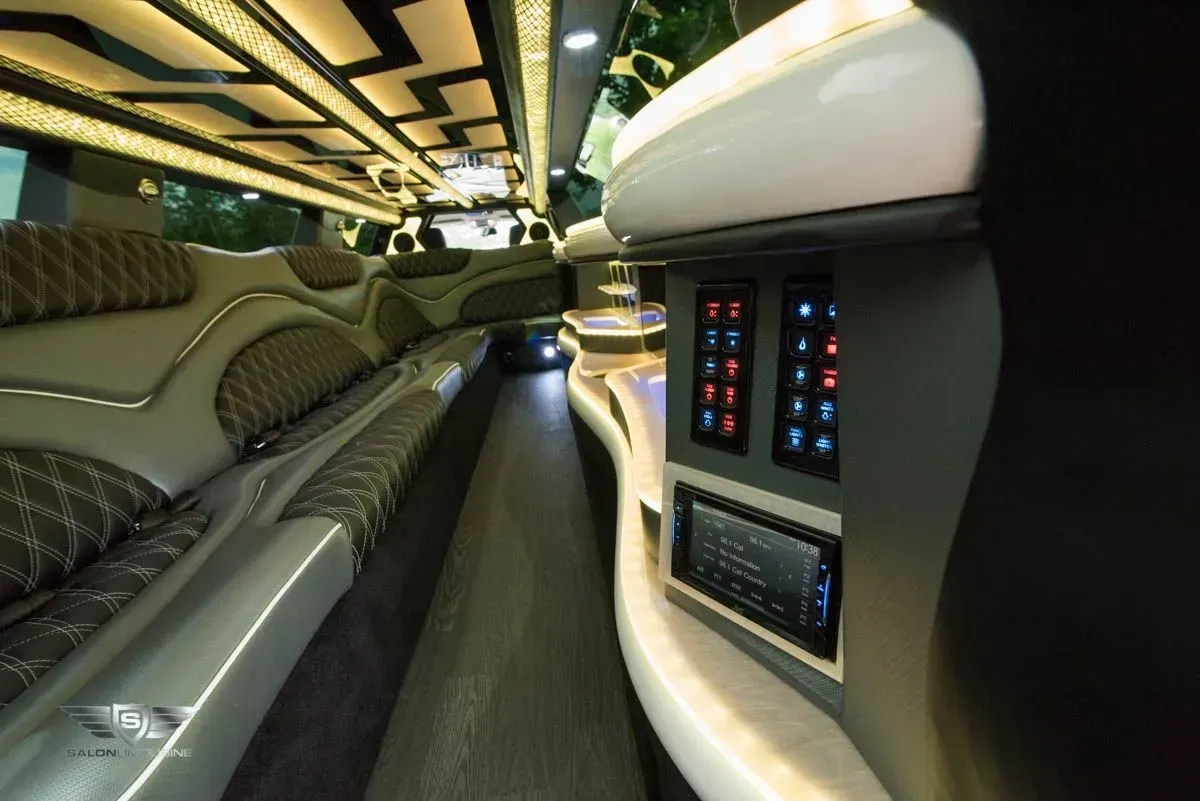 Interior of a luxury limousine, showing plush seating, lighting, and control panels.