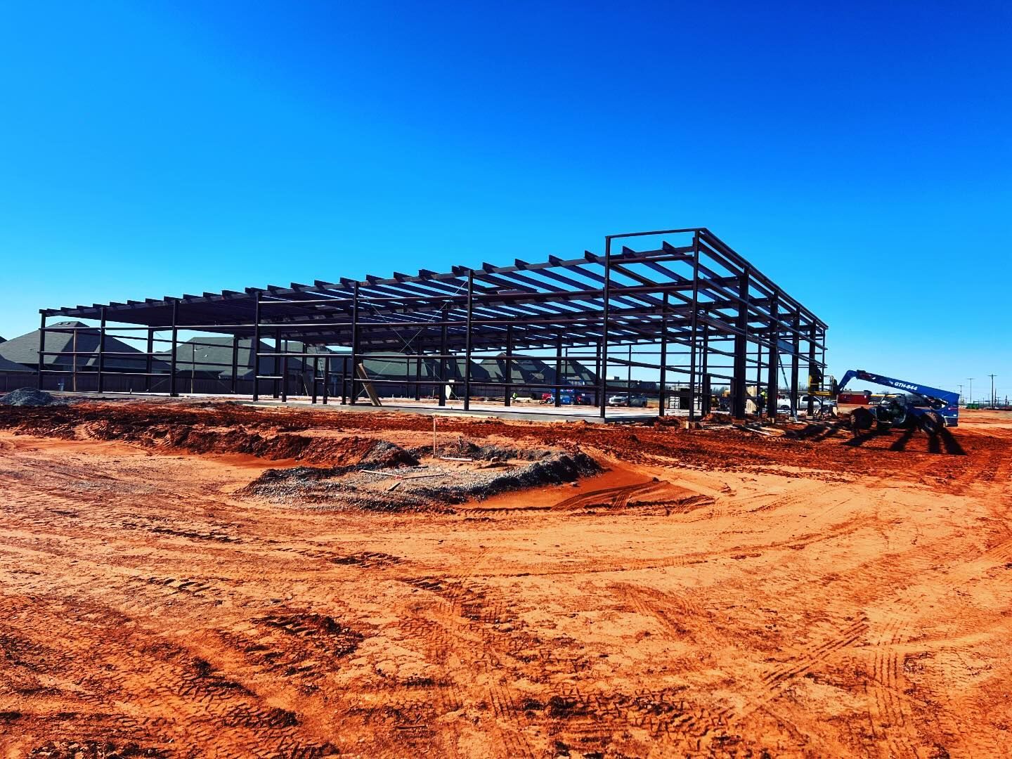 A large metal structure is being built in the middle of a dirt field.