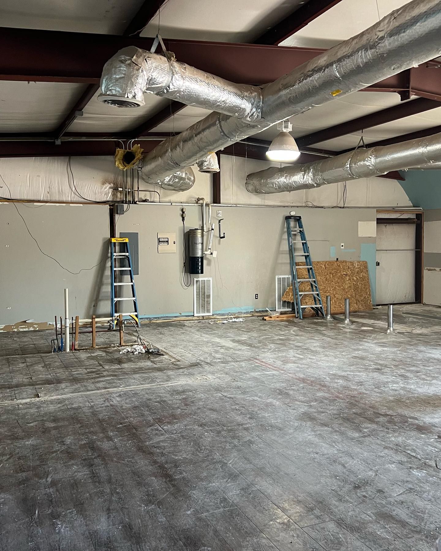 A large empty room with a lot of pipes hanging from the ceiling.