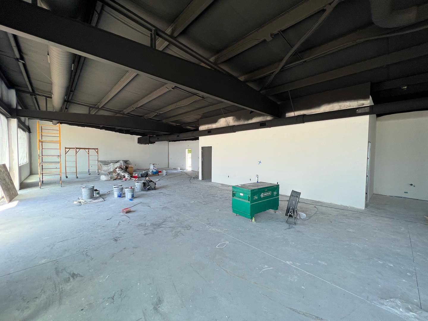 A large empty room with white walls and a green box on the floor.