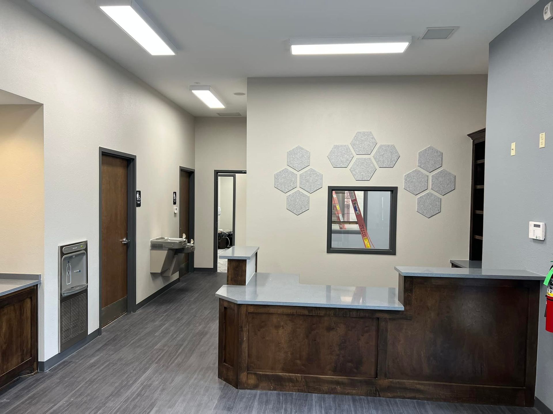 A reception area with a wooden counter and a mirror on the wall.