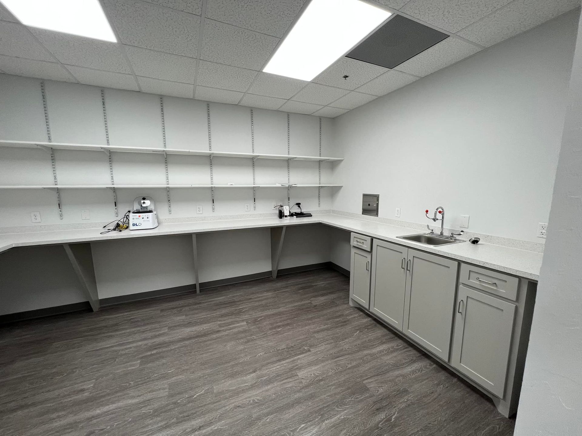 An empty kitchen with white cabinets and a sink