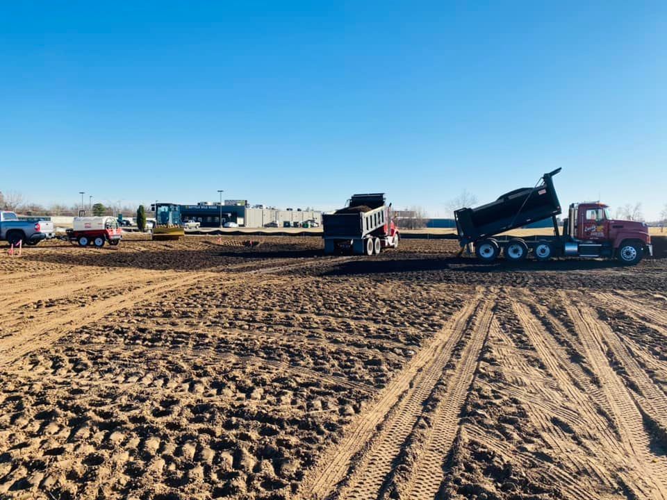 A dump truck is driving through a dirt field.