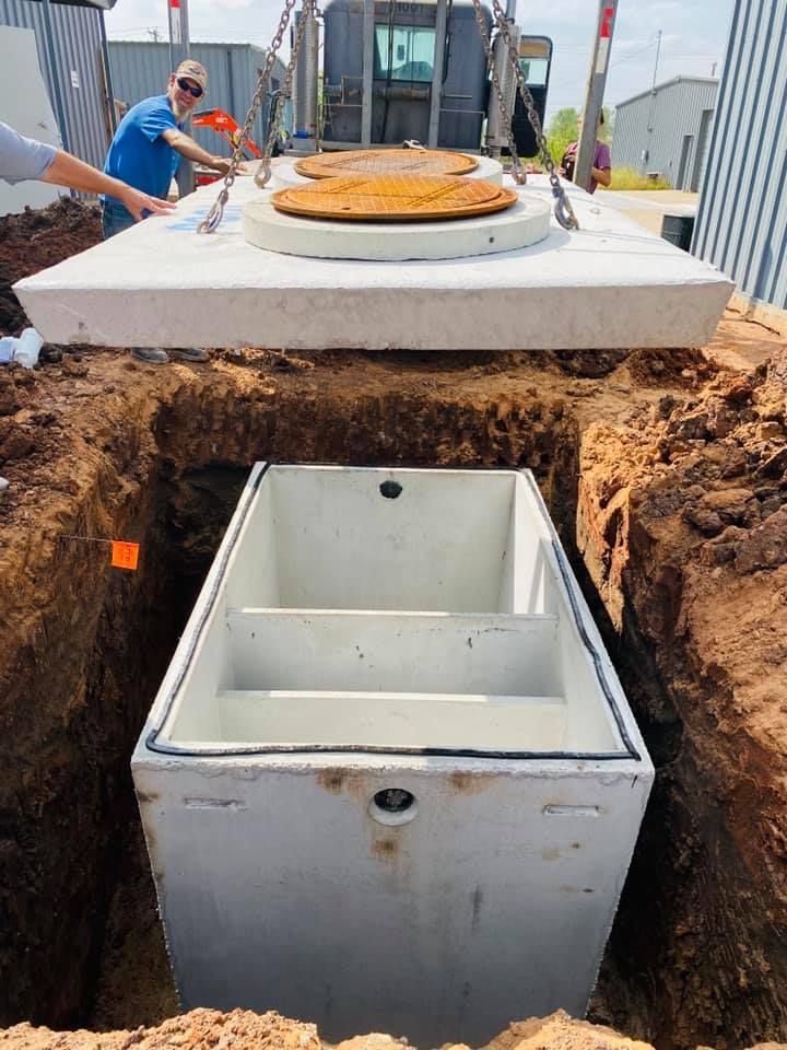 A concrete septic tank is being installed in a hole in the ground.