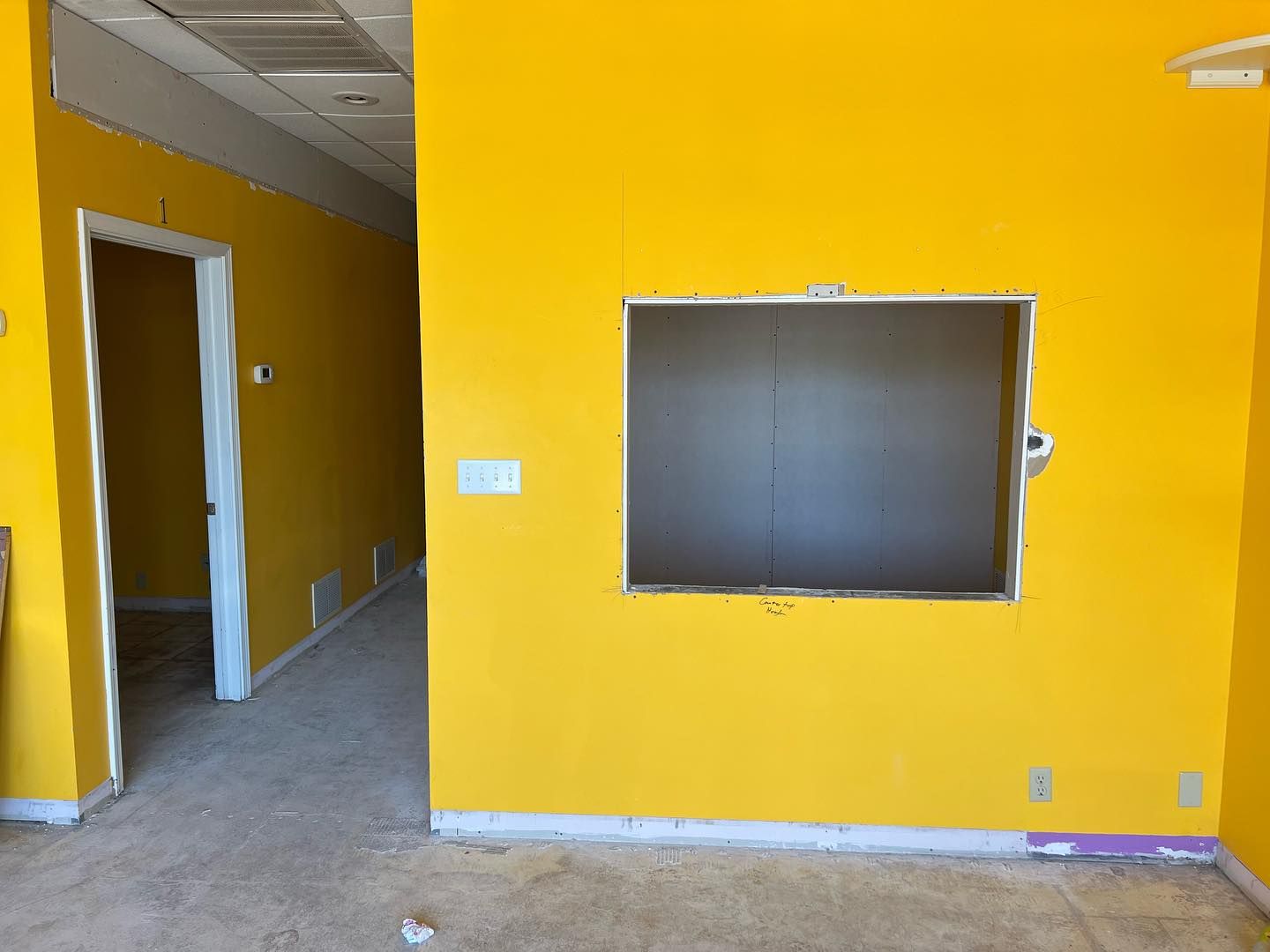 An empty room with yellow walls and a window.