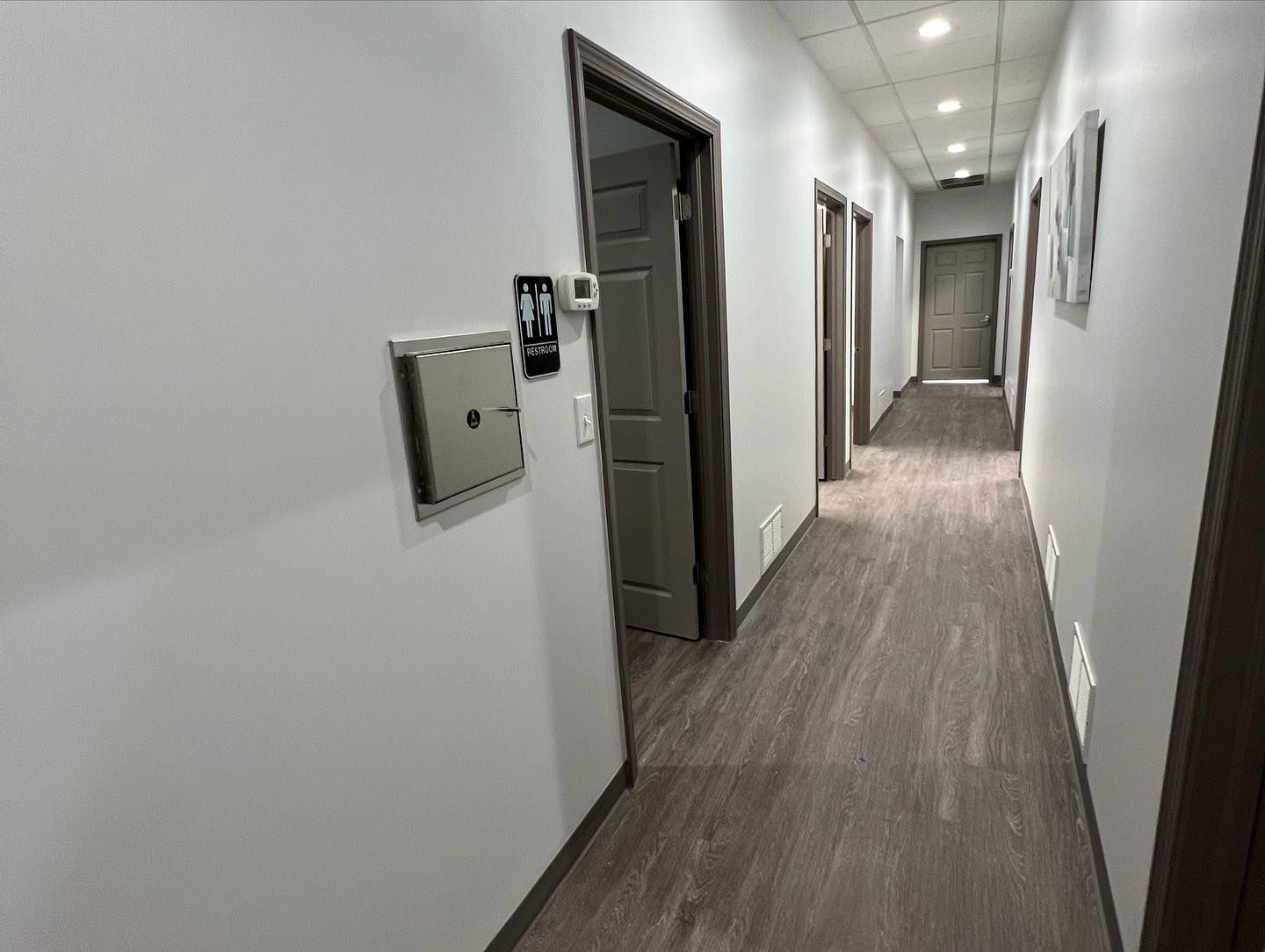 A long hallway with wooden floors and white walls in a building.