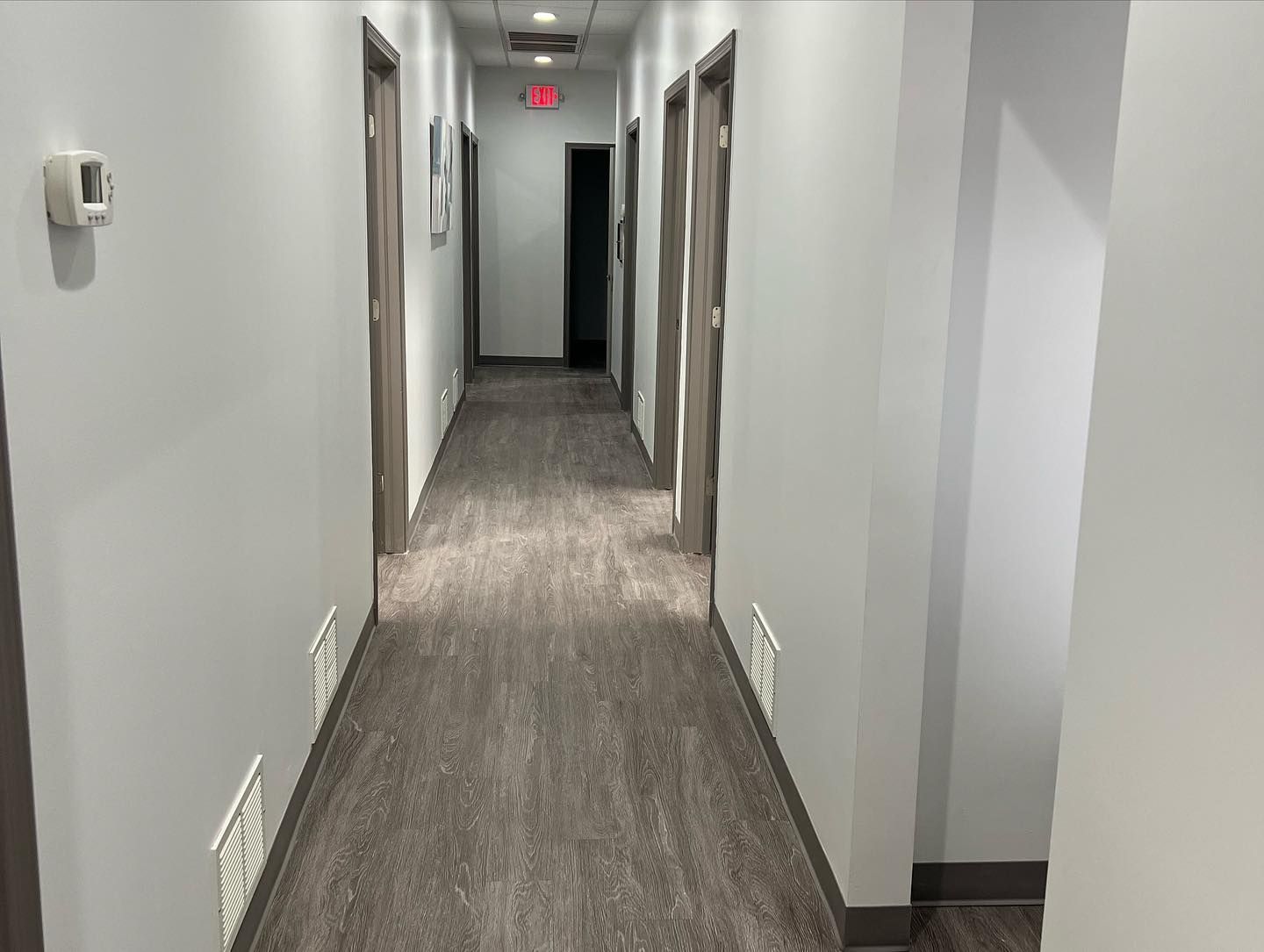 A long hallway in a building with a thermostat on the wall.
