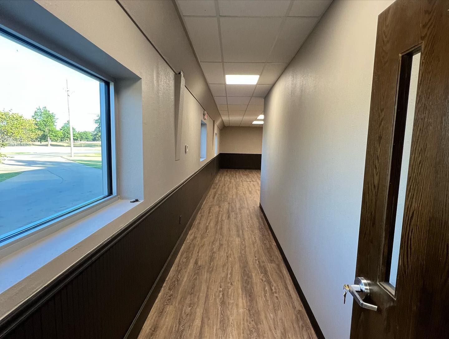 A long hallway with a window and a door in a building.
