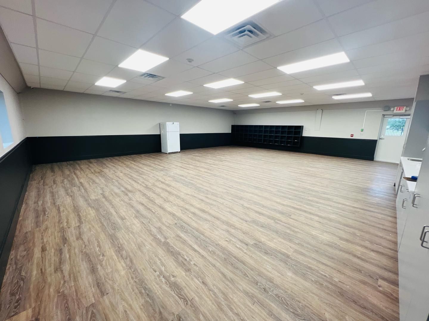 A large empty room with wooden floors and ceiling lights.