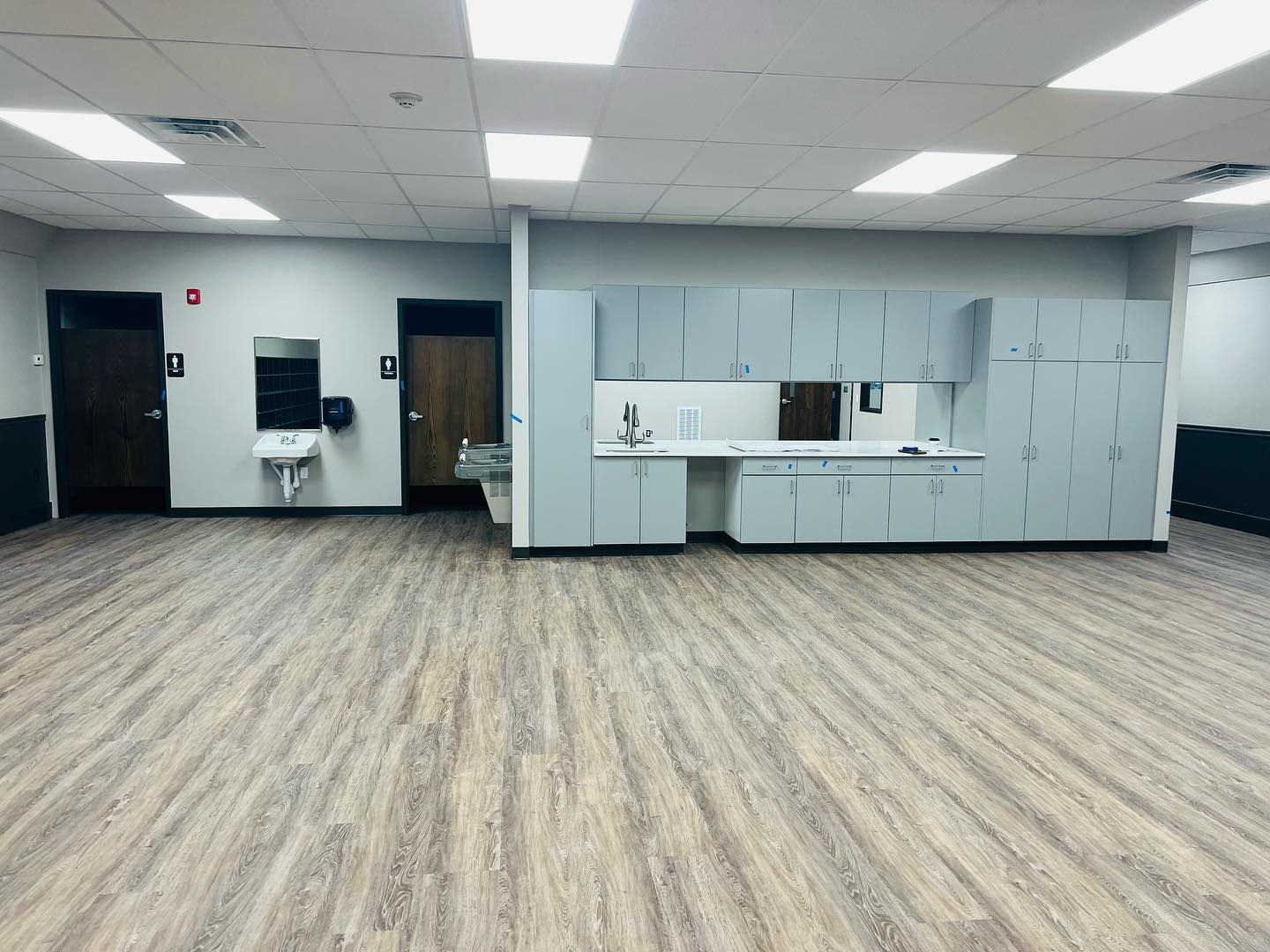 A large empty room with wooden floors and white cabinets.
