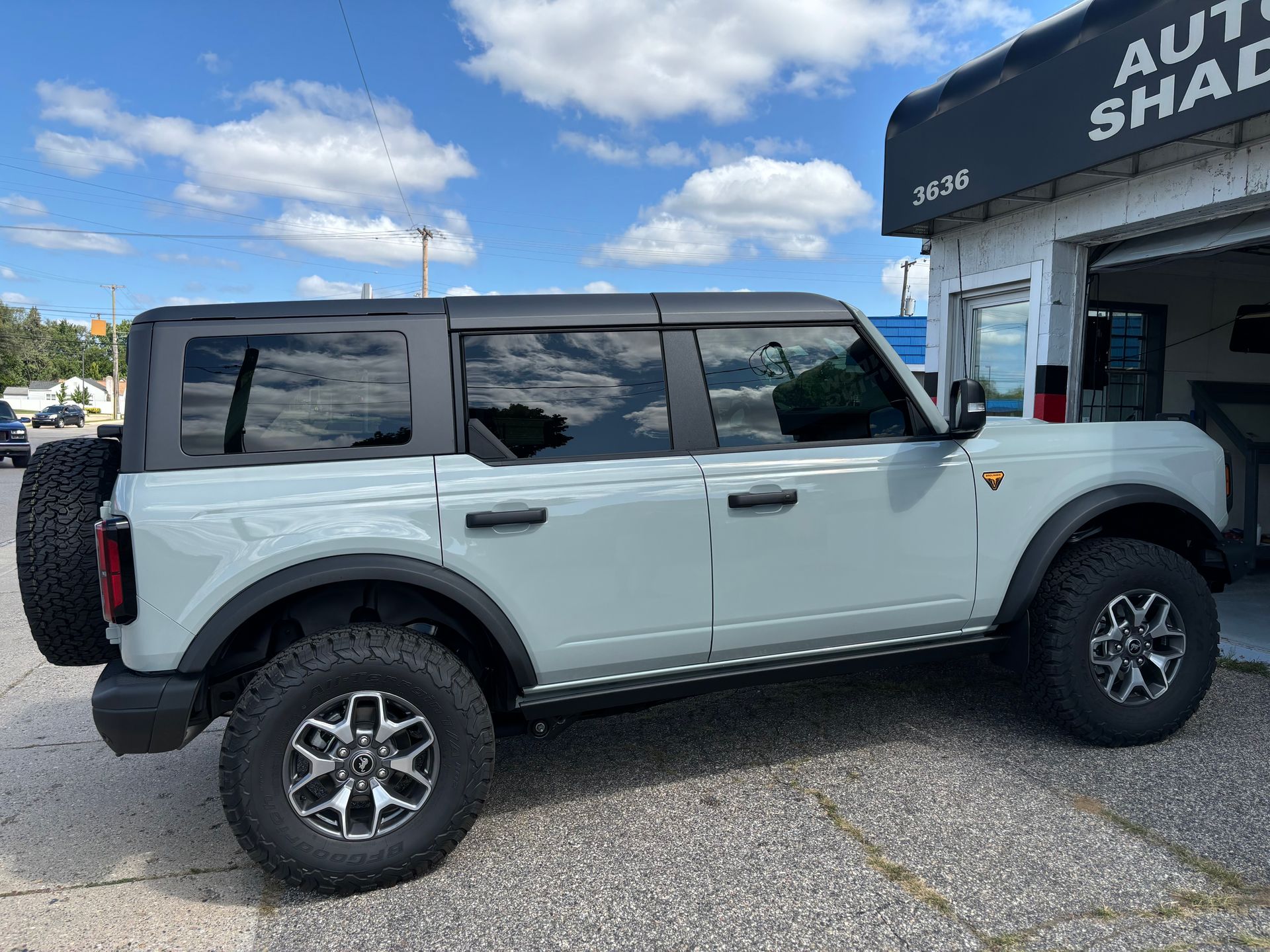 A white ford bronco is parked in front of a garage.