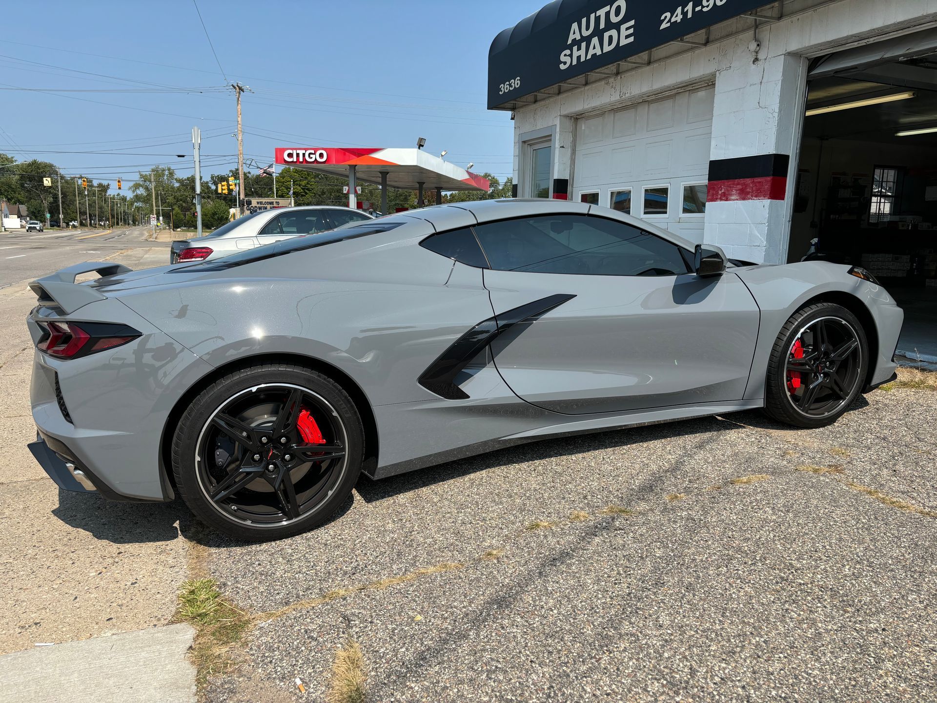 A gray sports car is parked in front of a garage.