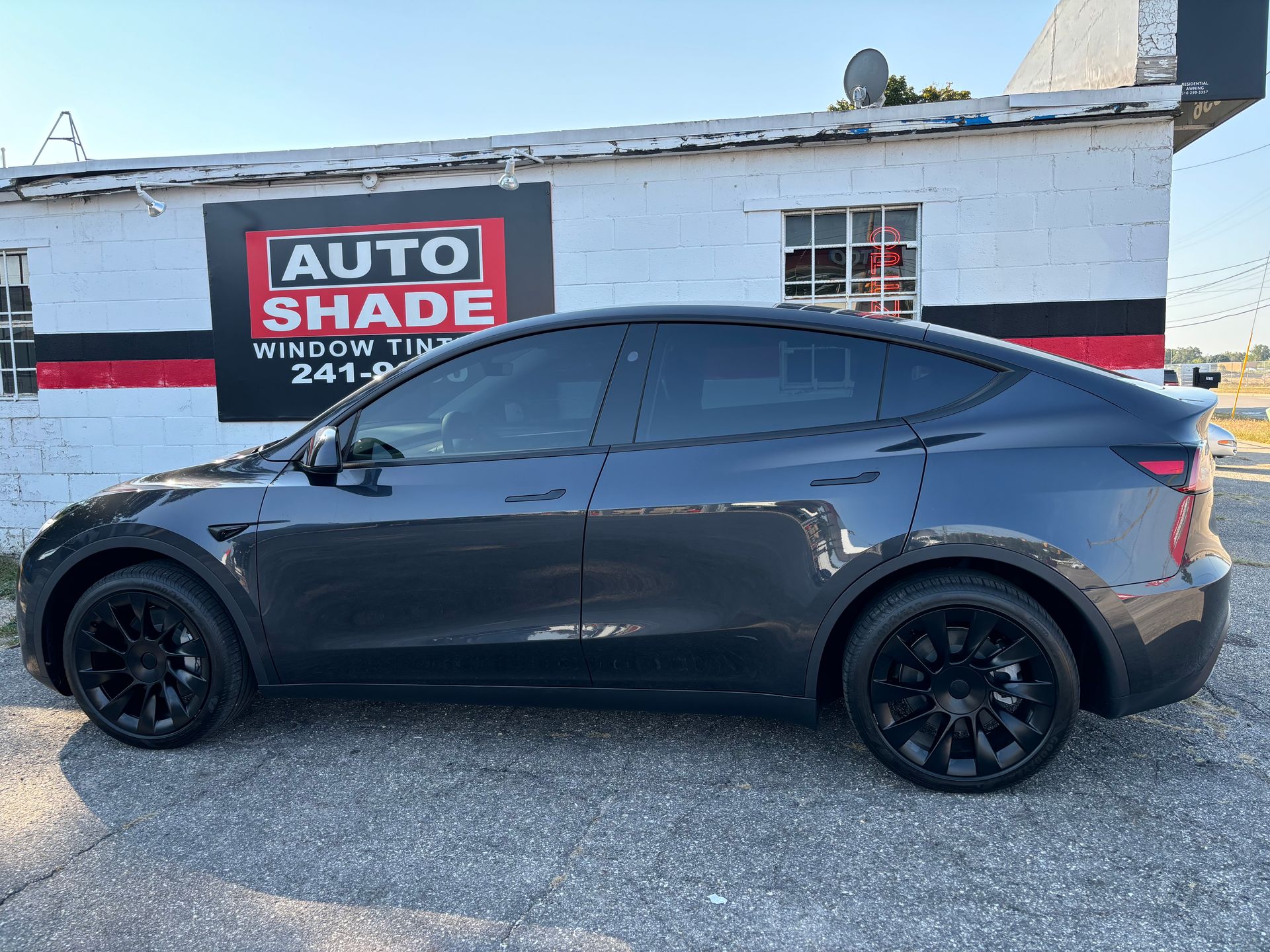 A black tesla model y is parked in front of a building.