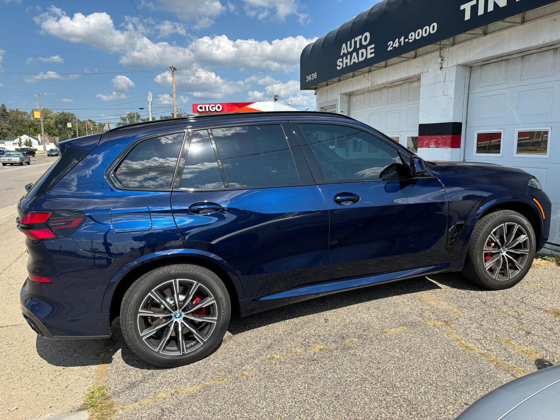 A blue bmw x5 is parked in front of a garage.
