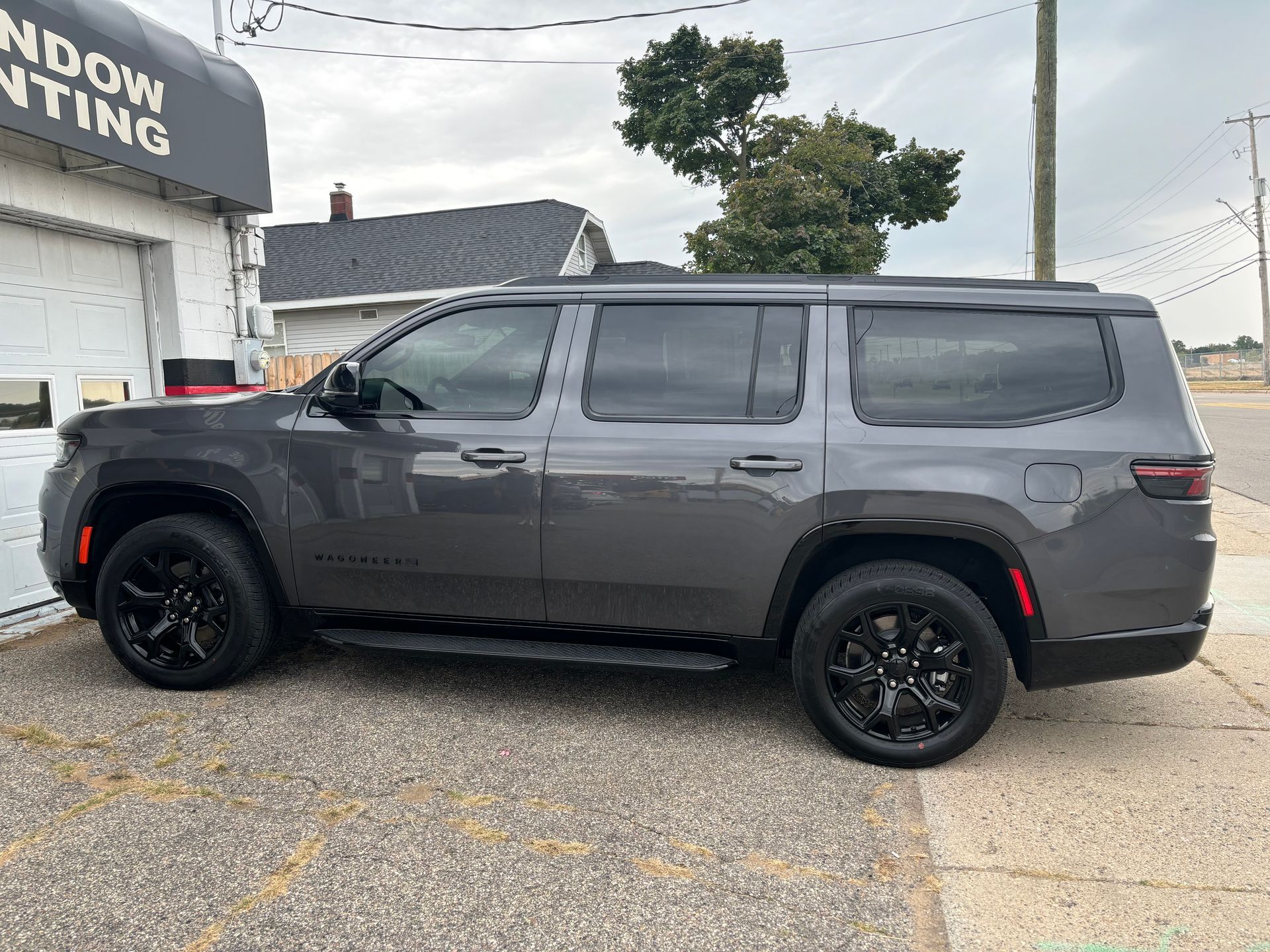 A gray suv is parked on the side of the road in front of a building.