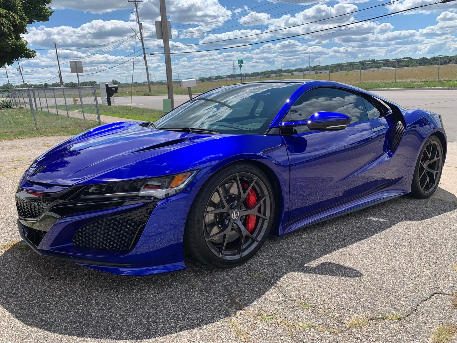 A blue sports car is parked on the side of the road.