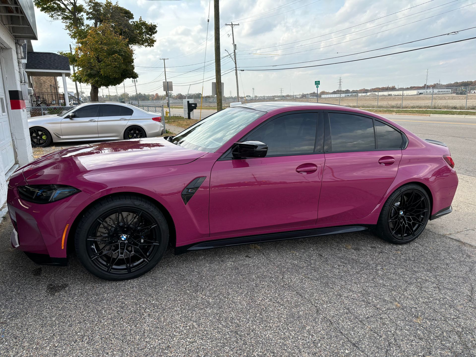 A pink bmw m3 is parked in a parking lot.