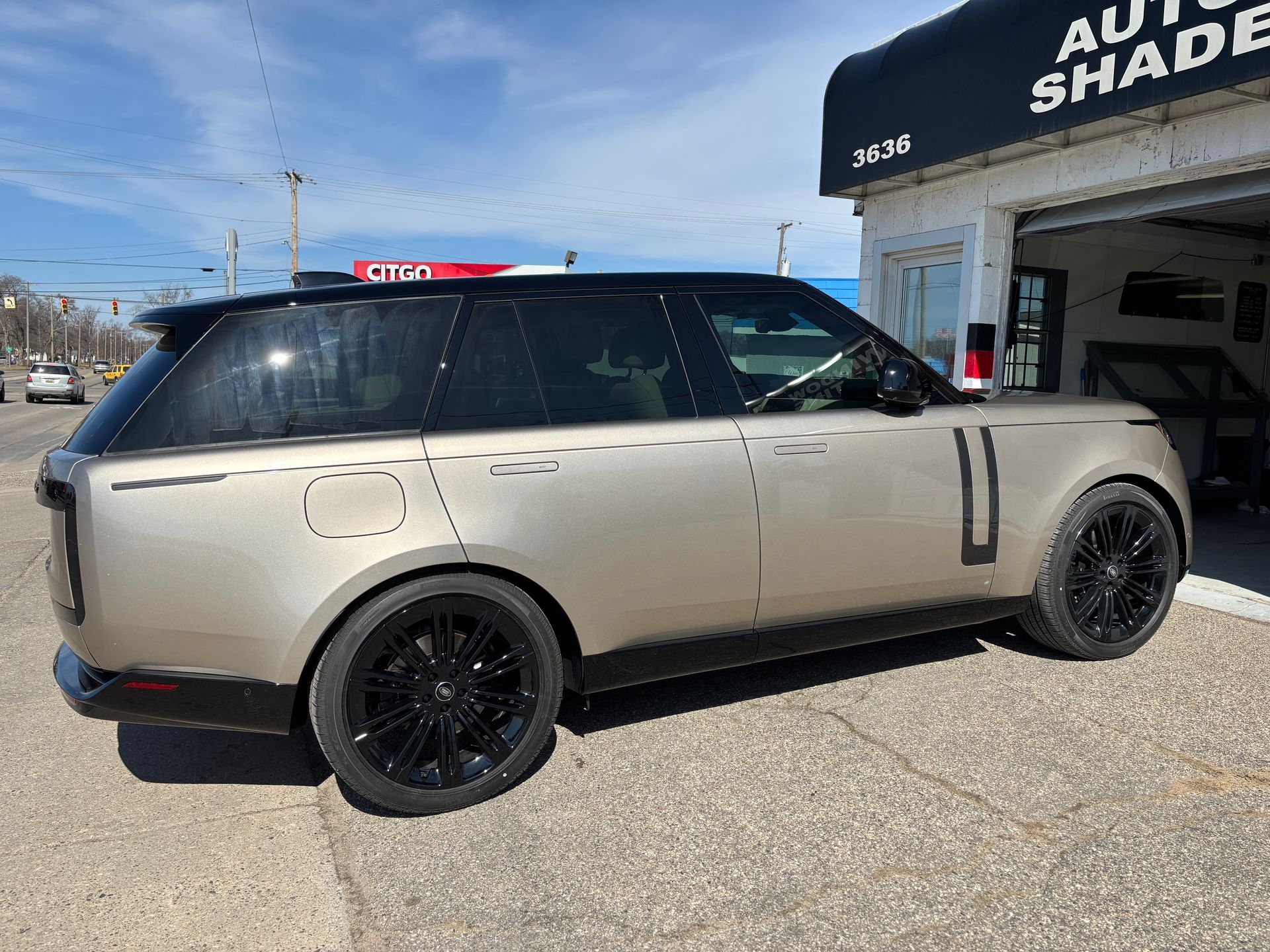 A range rover is parked in front of an auto shade shop.