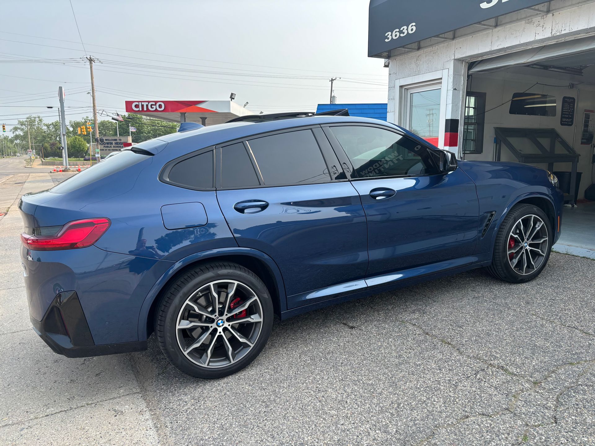 A blue bmw x4 is parked in front of a garage.