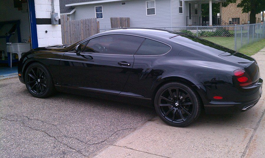 A black bentley is parked on the side of the road