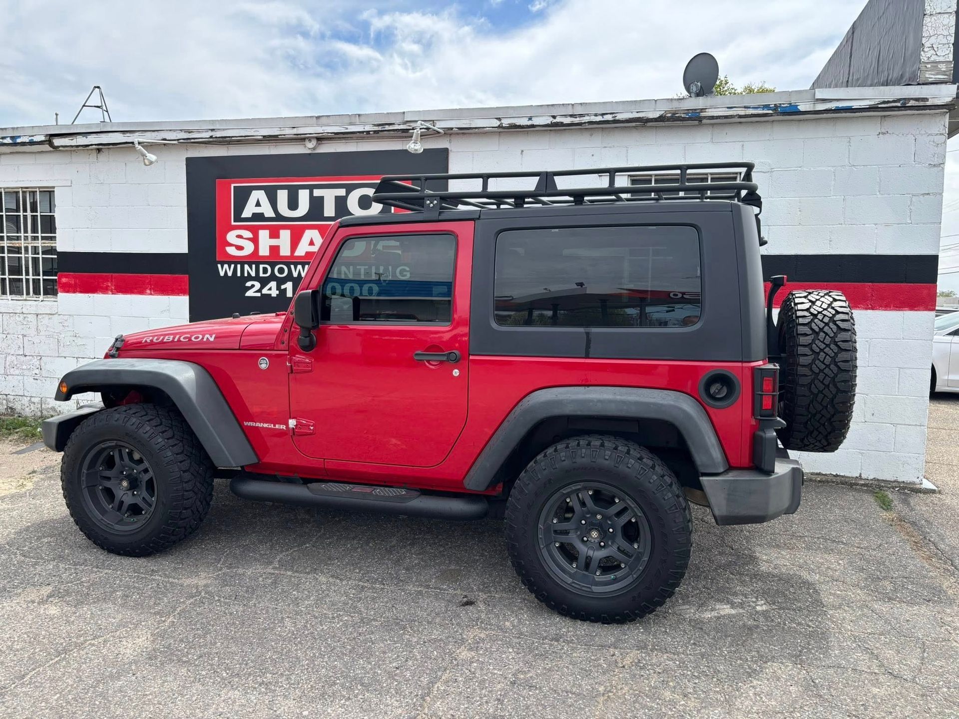 A red jeep is parked in front of a building.
