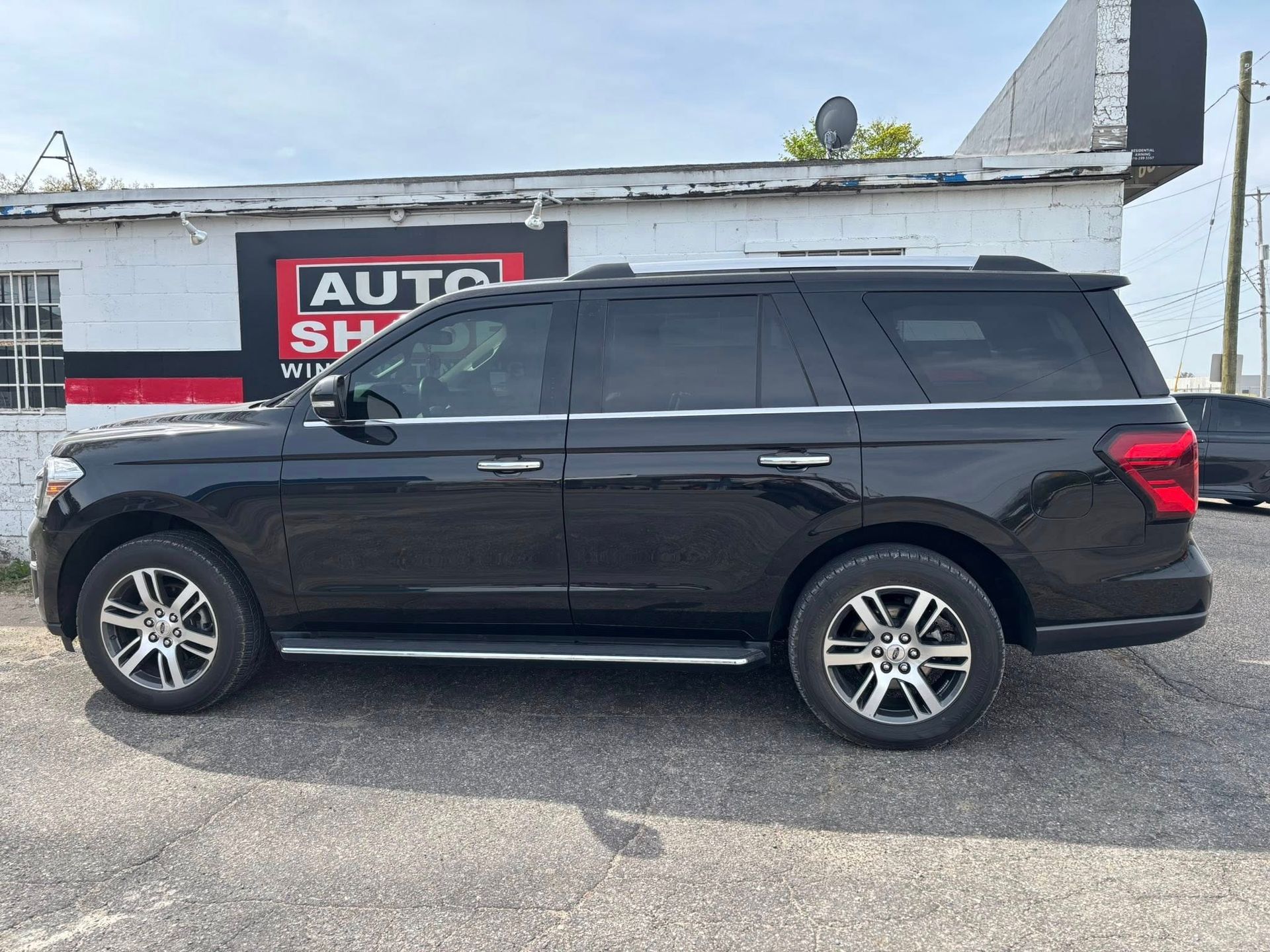 A black ford expedition is parked in front of a building.