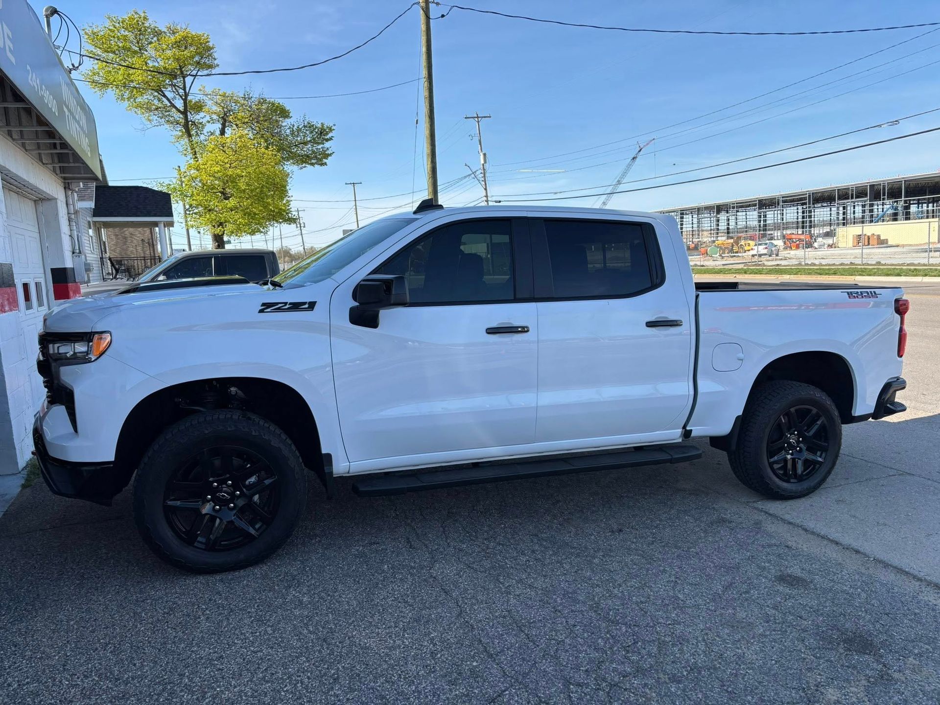 A white truck is parked on the side of the road in front of a building.