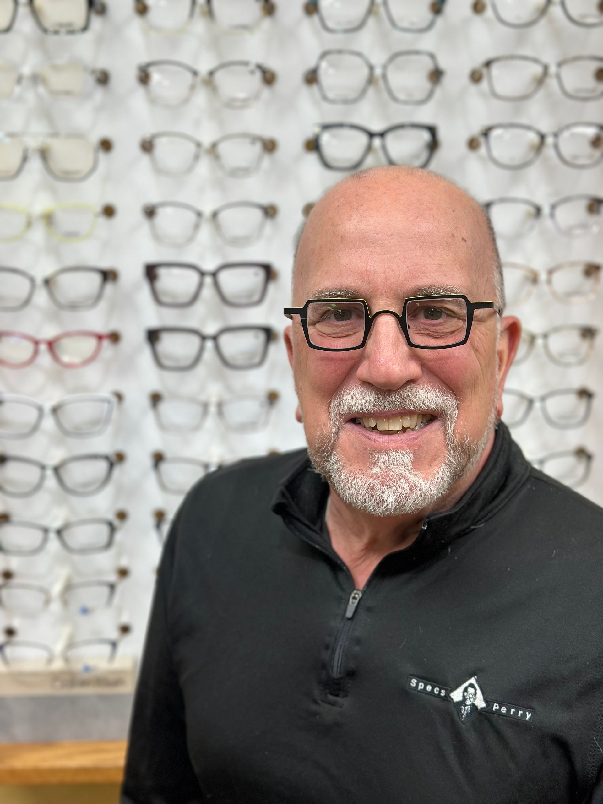 A man with glasses and a beard is smiling.