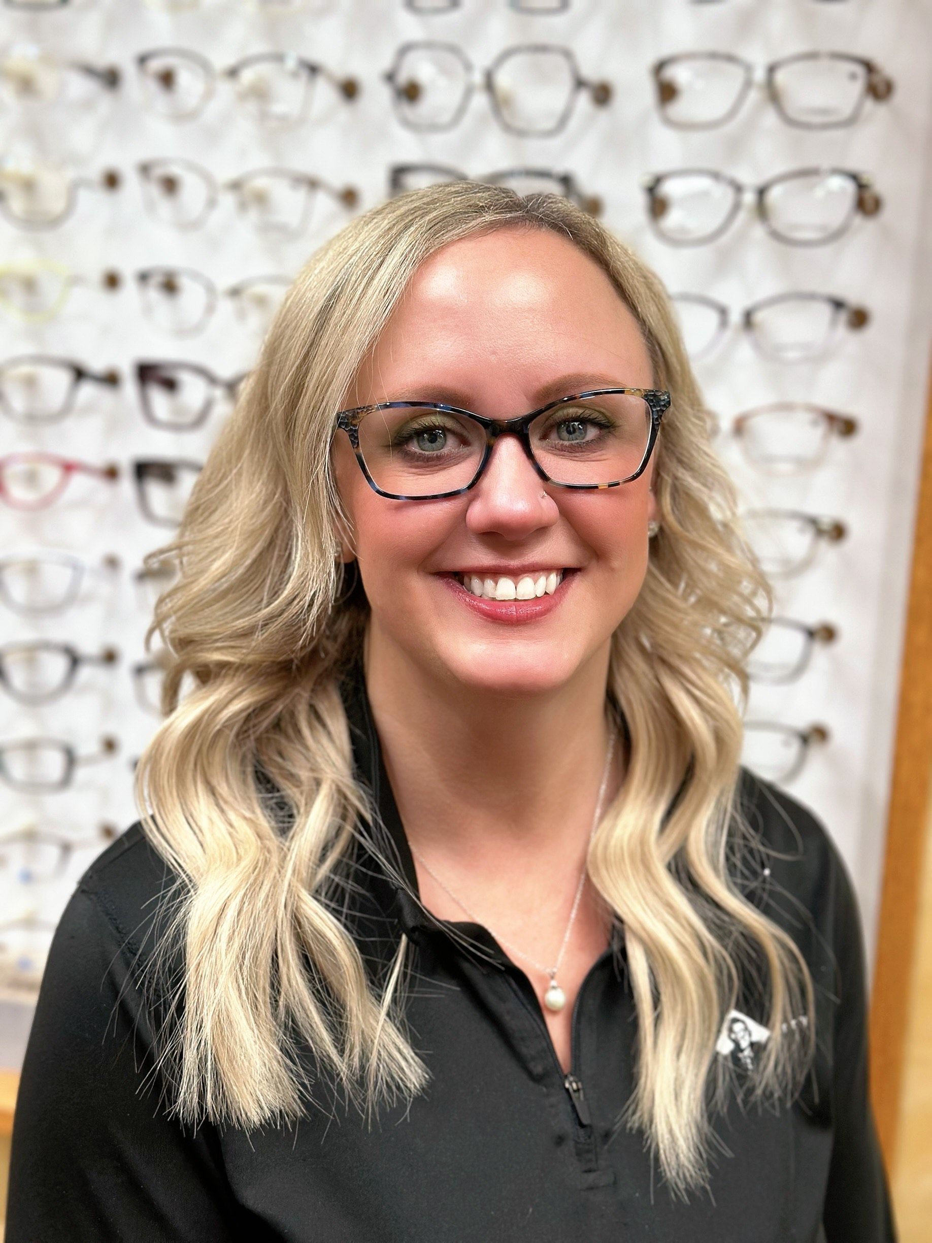 A woman wearing glasses and a black shirt is smiling.