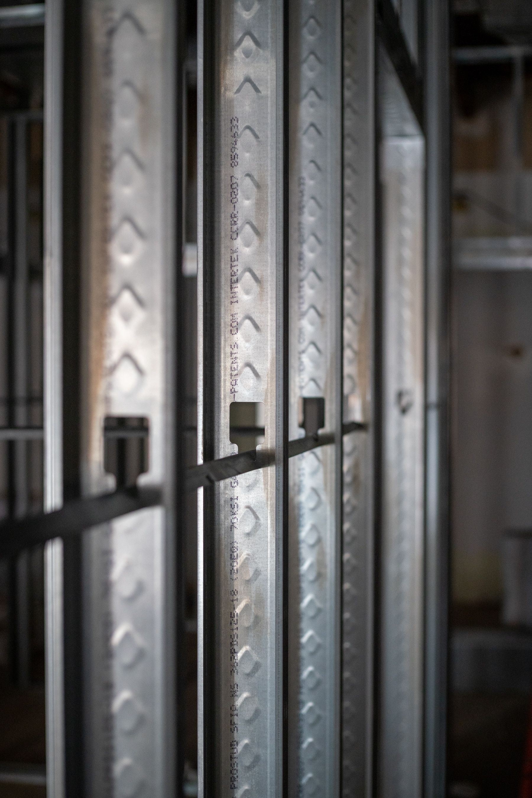 Close-up of vertical light-gauge steel wall studs joined by a horizontal metal furring channel.
